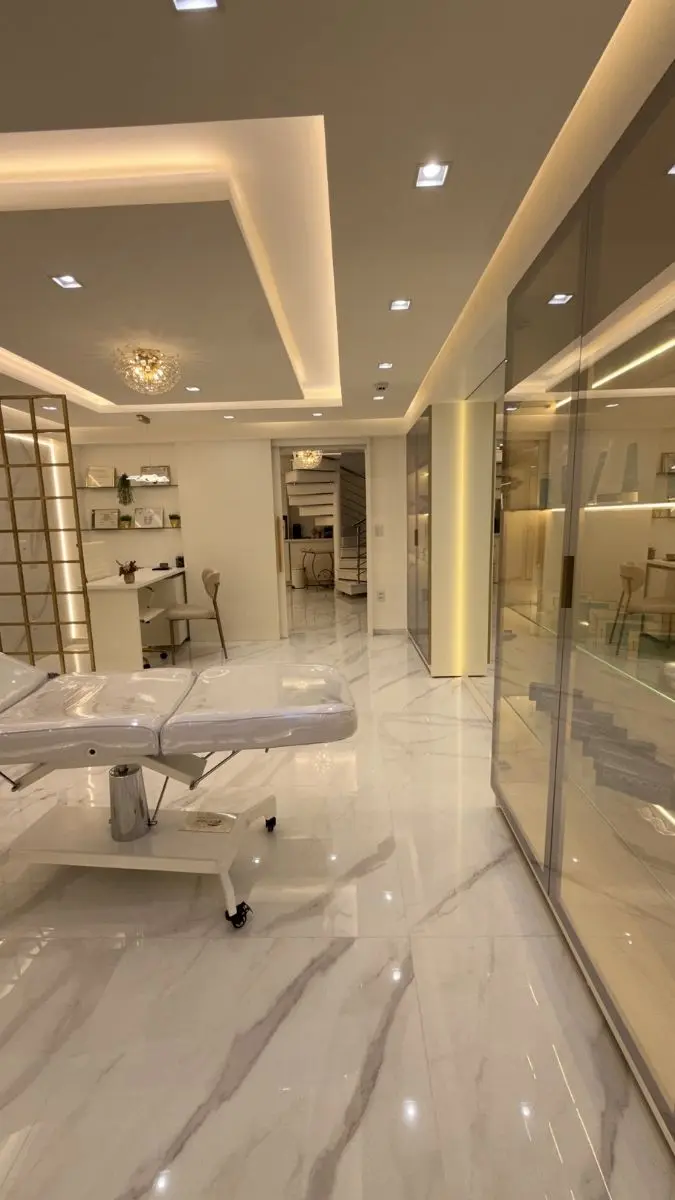 Infraestrutura completa da clínica de estética avançada, destacando a maca centralizada e armários planejados para organização rigorosa de materiais.