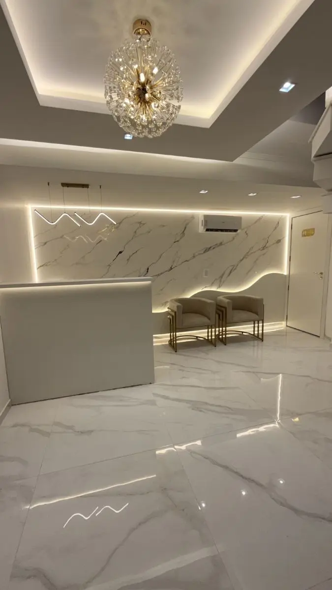 Recepção moderna e acolhedora da clínica de harmonização facial no Centro de Canoas, com piso em porcelanato claro e poltronas de espera.