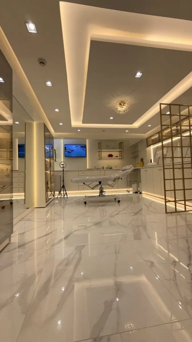 Ângulo evidenciando o piso em porcelanato marmorizado e a maca clínica, reforçando a assepsia e o conforto da sala de procedimentos injetáveis.