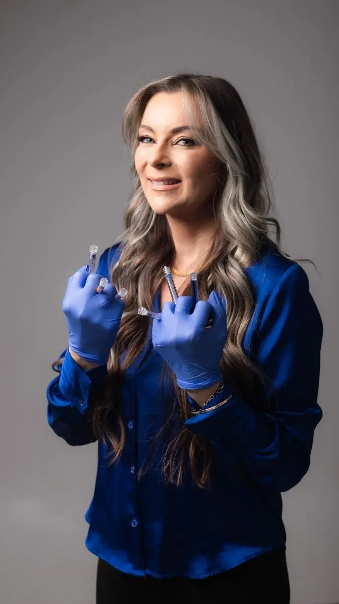 Profissional com luvas de procedimento segurando múltiplas seringas, evidenciando a utilização de materiais clínicos para estética avançada.